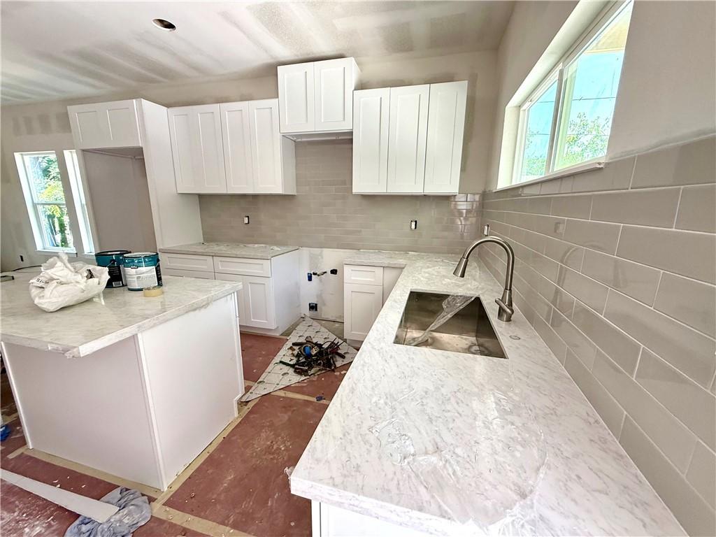 Image 4: Kitchen with tasteful backsplash, light stone coun