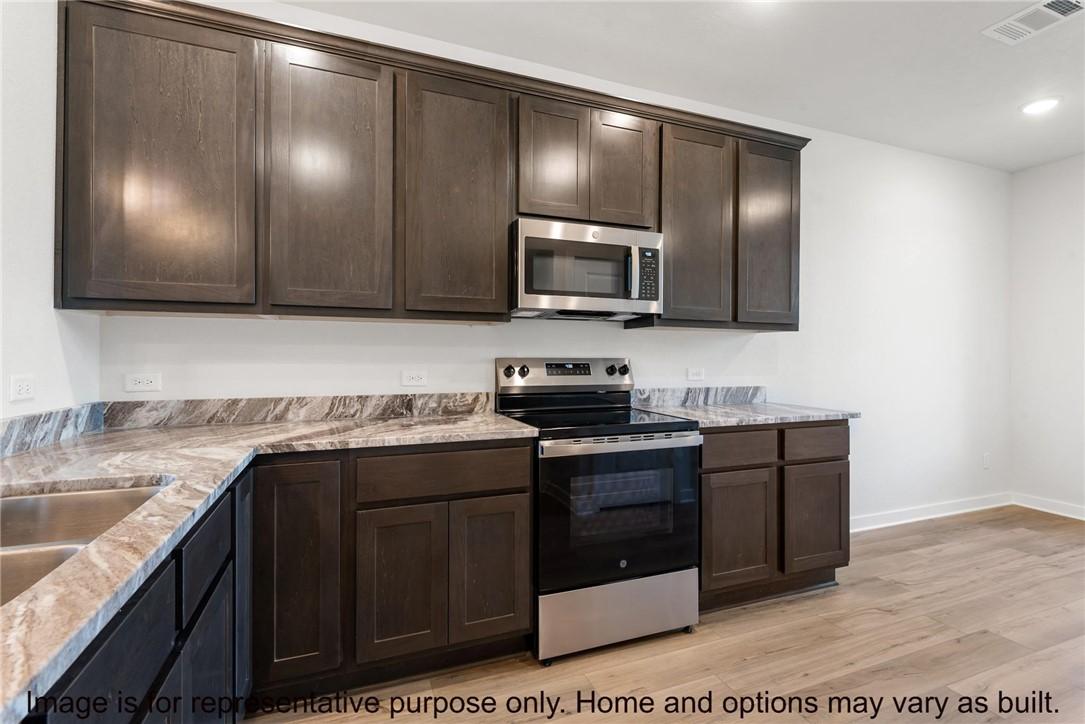 Image 4: Kitchen with dark brown cabinetry, appliances with