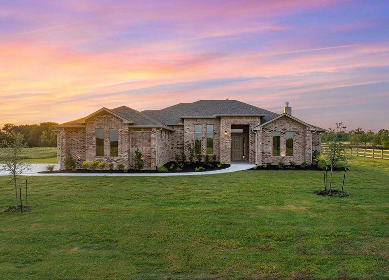 Image 2: View of front of property with brick siding and a