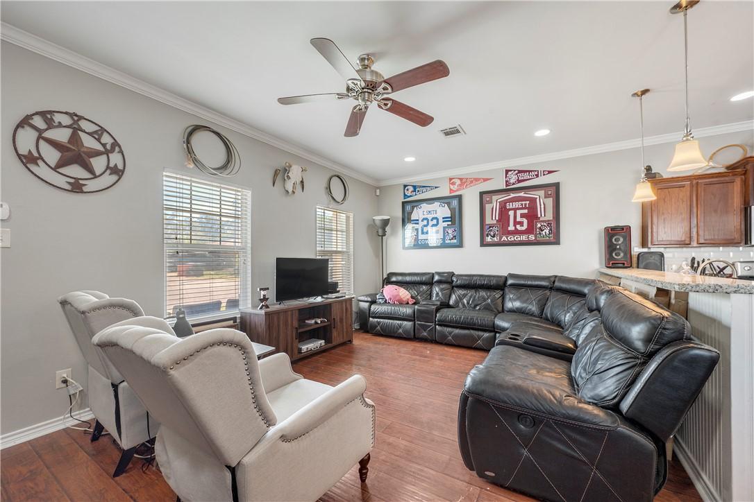 Image 3: Living area with crown molding, dark wood-style fl
