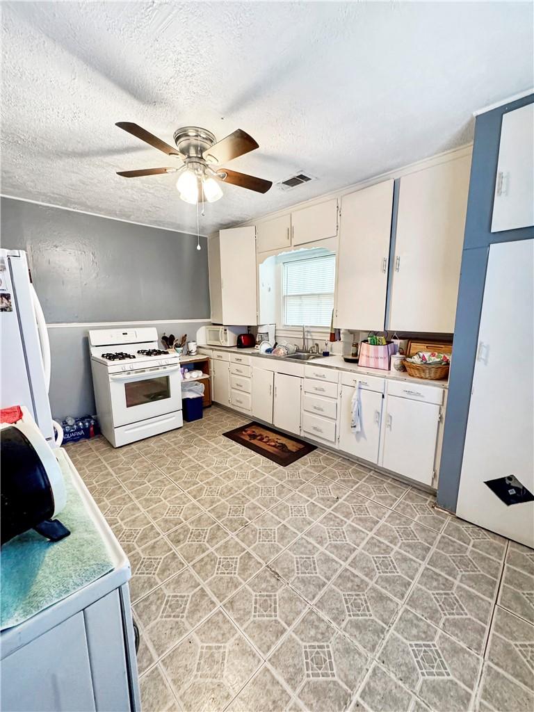 Image 4: Kitchen with white cabinetry, light countertops, w