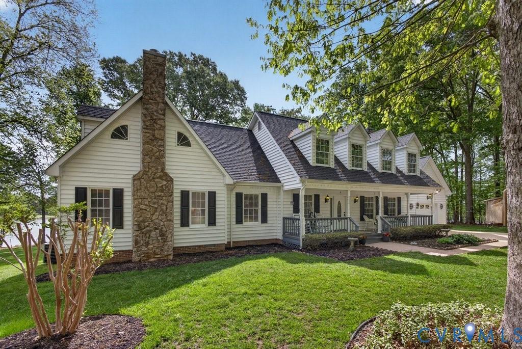 Image 2: This property features white siding, a stone chimn
