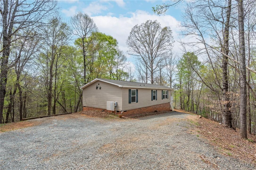 Image 4: View of home's exterior with gravel driveway and c