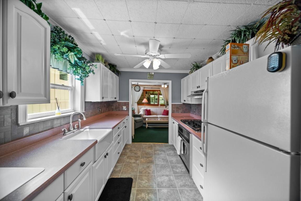 Image 3: The remodeled galley-style kitchen features white