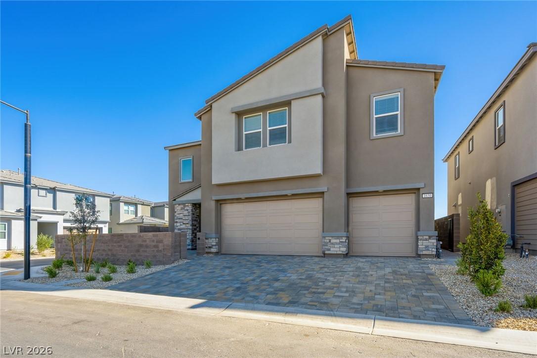 Image 2: A modern two-story home with a paver driveway and