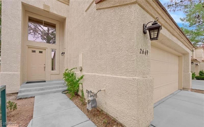 Image 3: Doorway to property with stucco siding and a garag