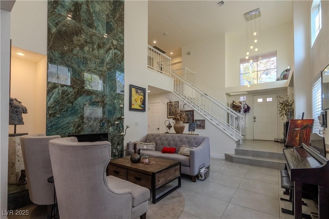 Image 2: Tiled living room featuring a high ceiling, stairs