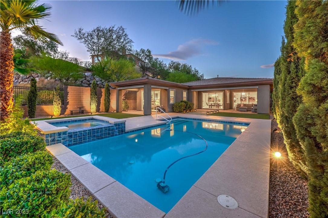 Image 1: Pool at dusk with a patio area and a pool with con