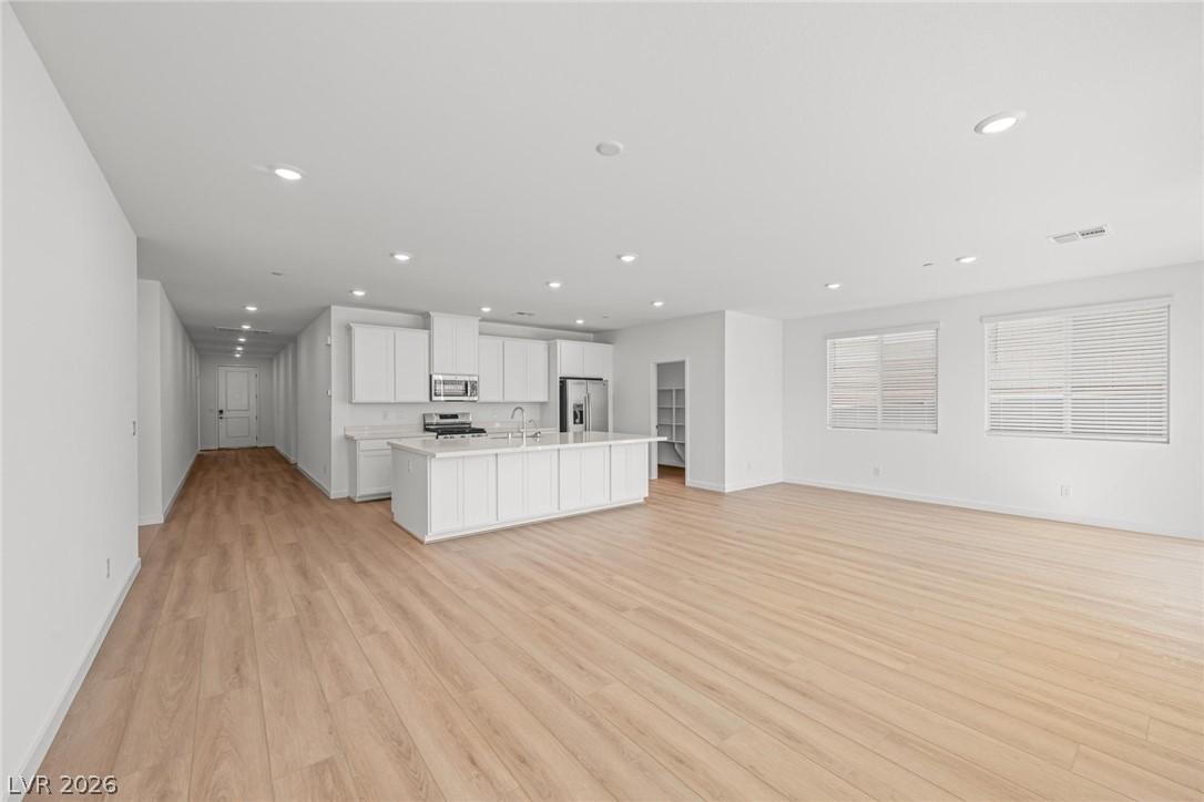 Image 3: An open-concept living area features light wood fl