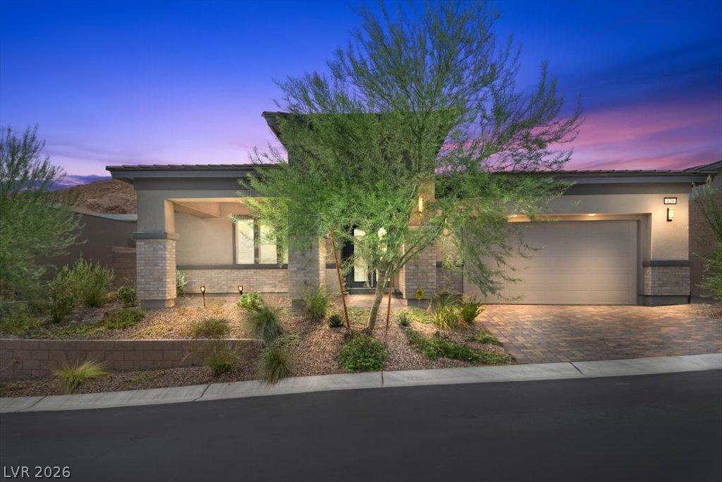 Image 1: A desert-modern home with paver driveway and natur