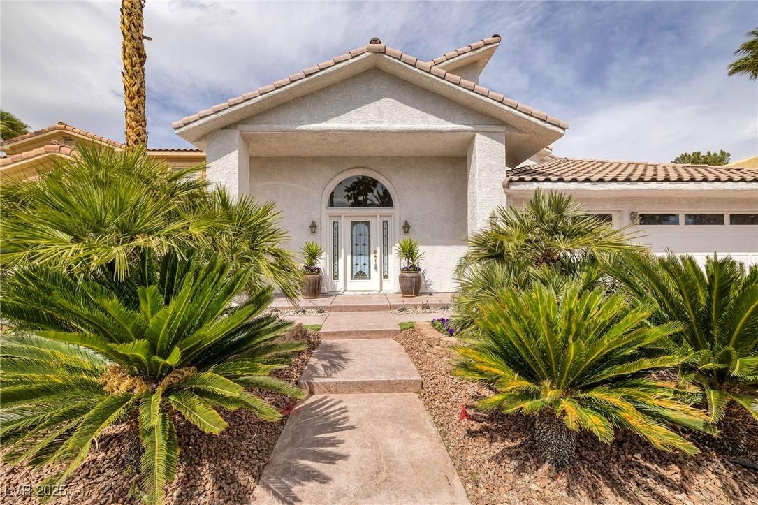 Image 3: Property entrance with a tile roof, a garage, and