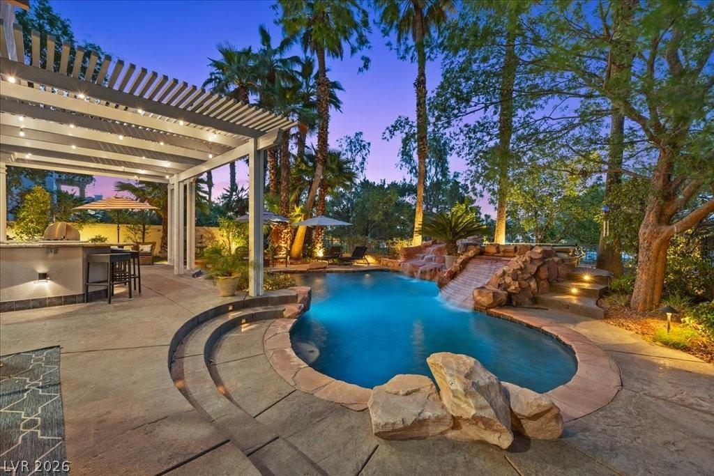 Image 3: An illuminated backyard oasis featuring a pergola-