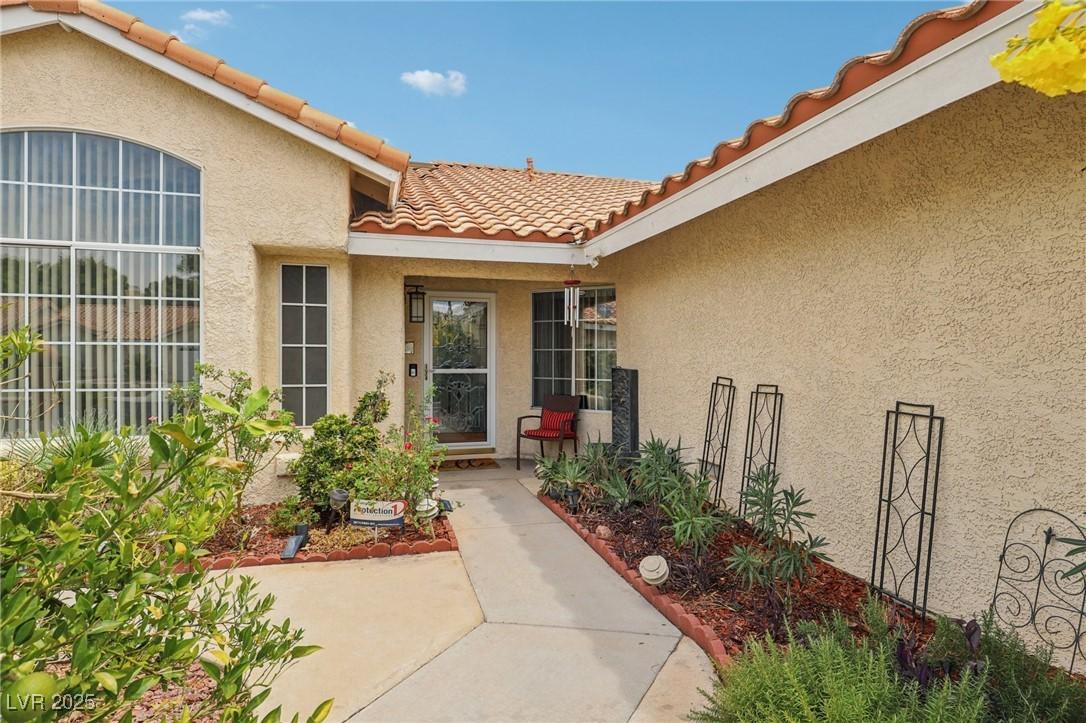 Image 3: Doorway to property with a tile roof and stucco si