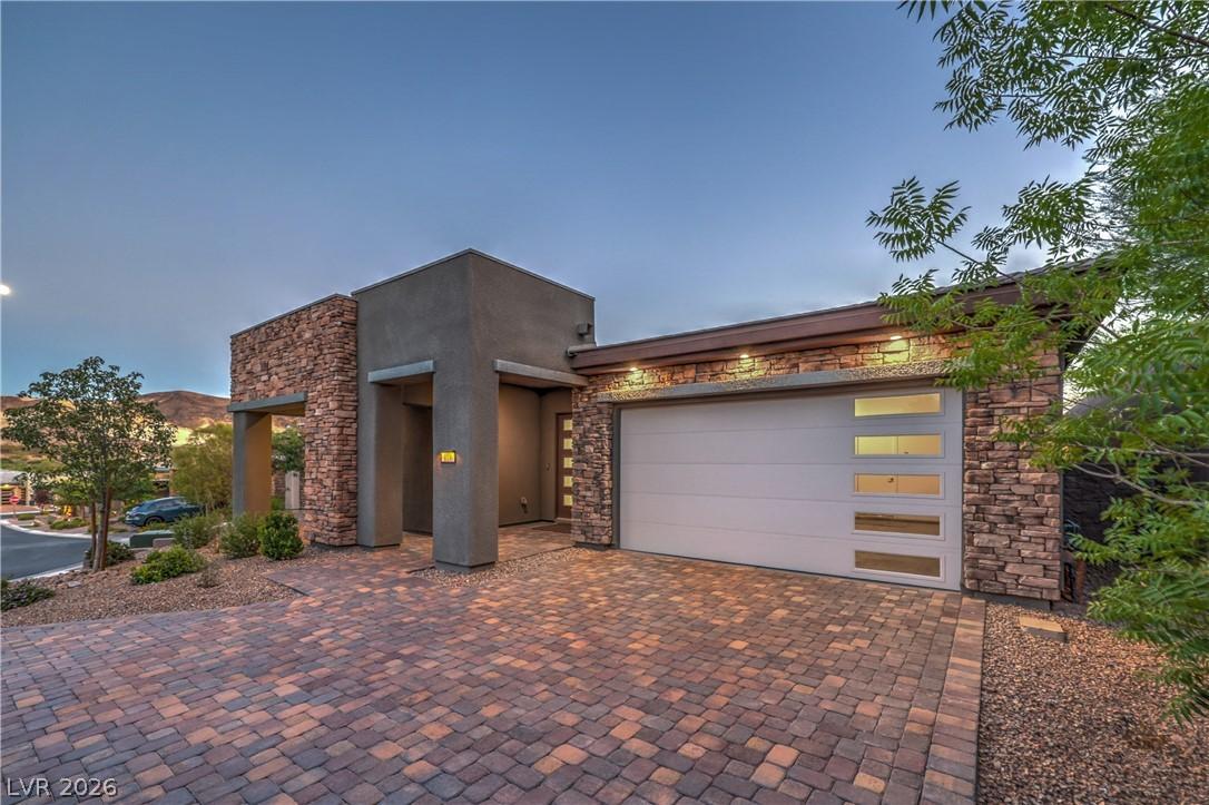 Image 3: A modern facade with stone accents and a paver dri