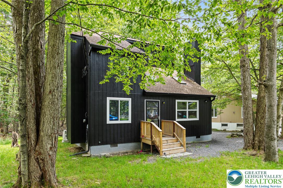 Image 2: A dark-toned dwelling emerges from a verdant backd