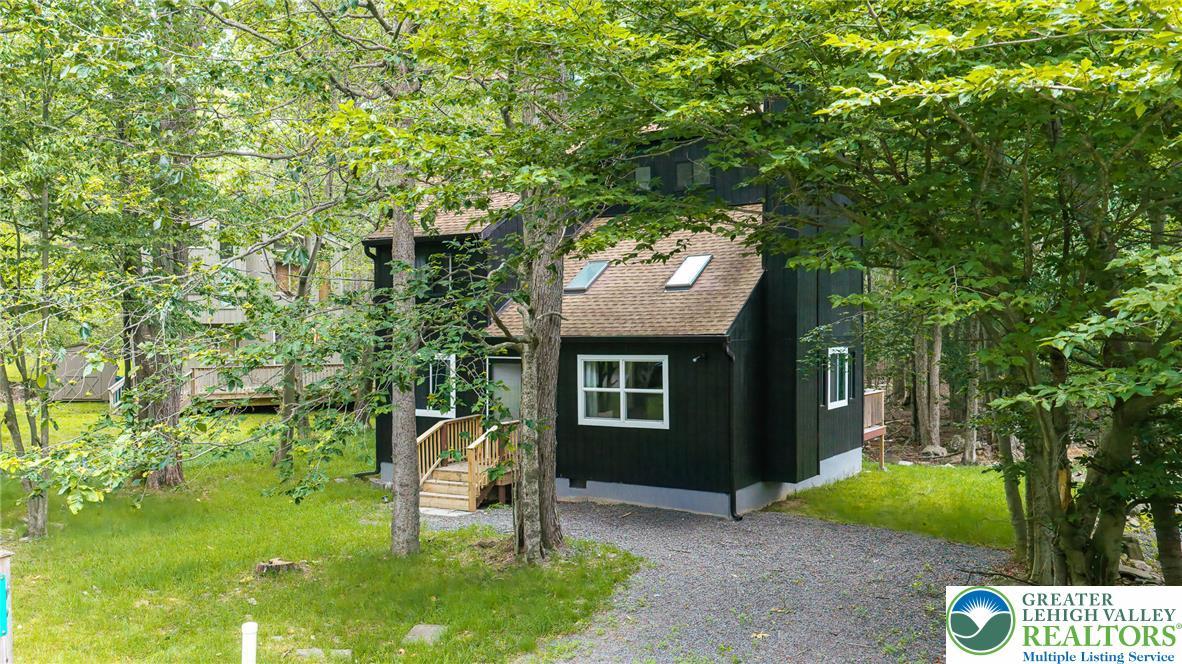 Image 3: A private driveway leads to this charming woodland