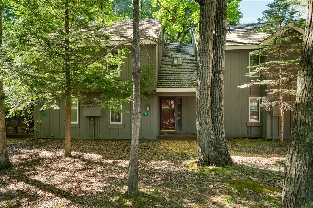 Image 1: Mature trees frame the front of this rustic reside