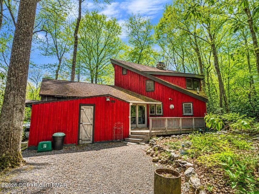 Image 2: A vibrant red siding home nestled among lush trees