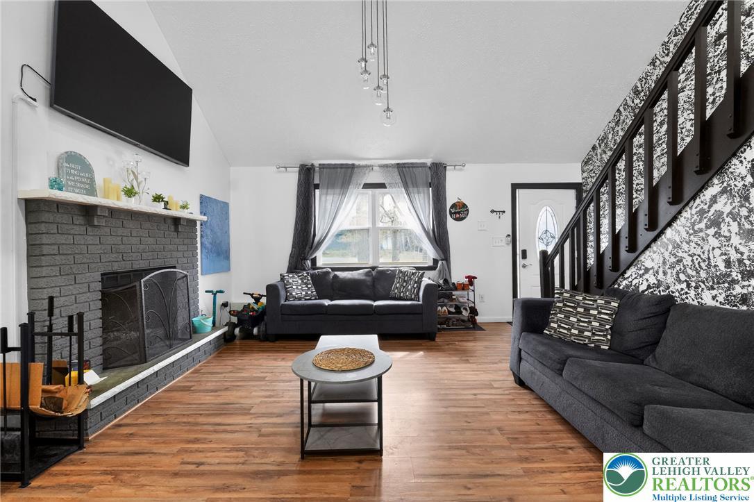 Image 2: This living room features rich wood flooring, a fi
