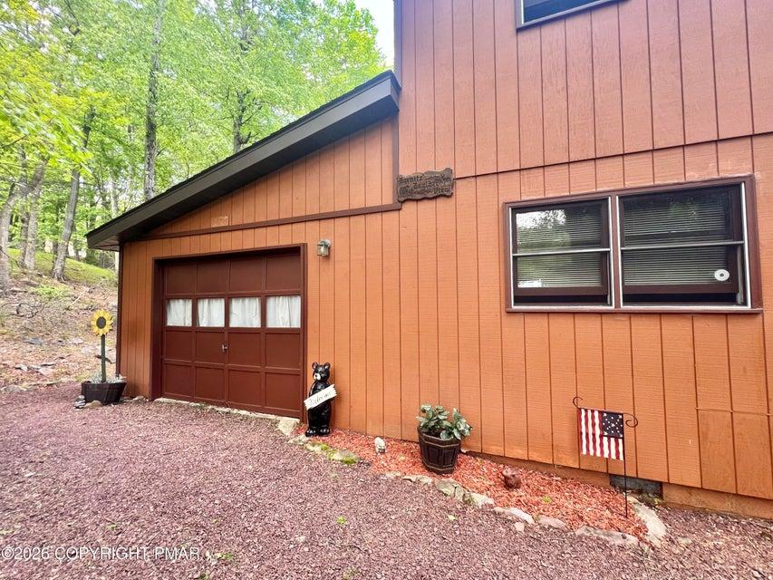 Image 3: Wood siding and a single garage door create a char