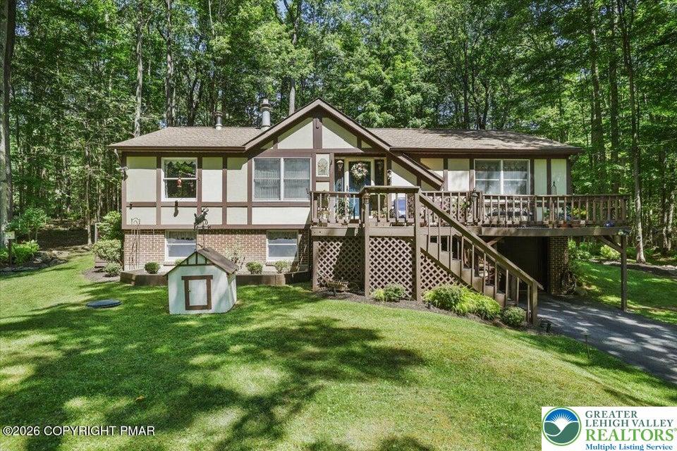 Image 1: A split-level home with a spacious deck and wooded