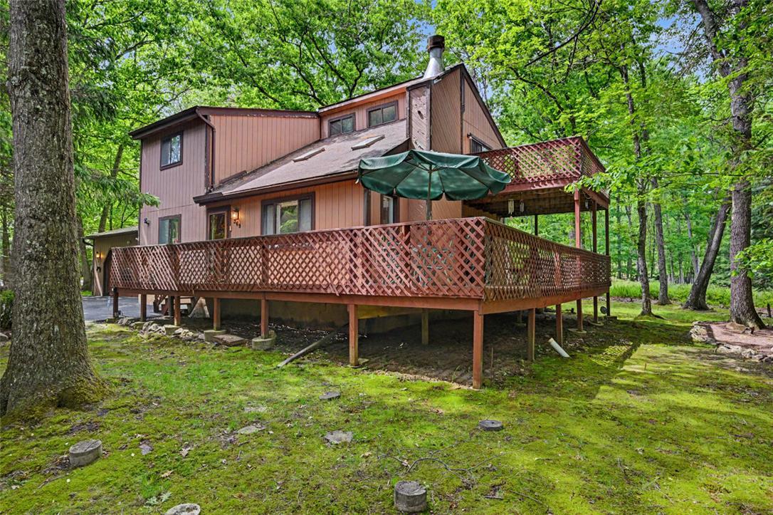 Image 3: A spacious wooden deck extends from a rustic, mult