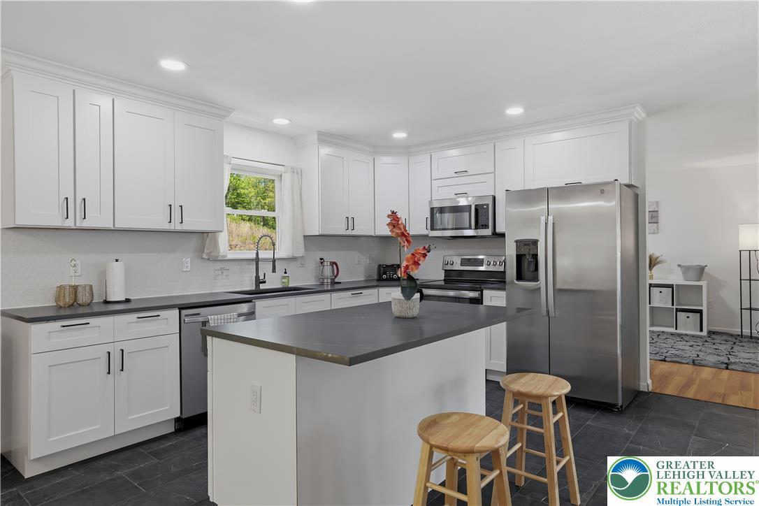Image 3: White cabinetry, stainless appliances, and a centr