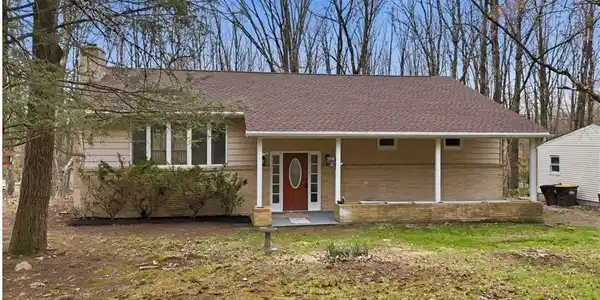Image 2: A welcoming covered porch and red front door disti