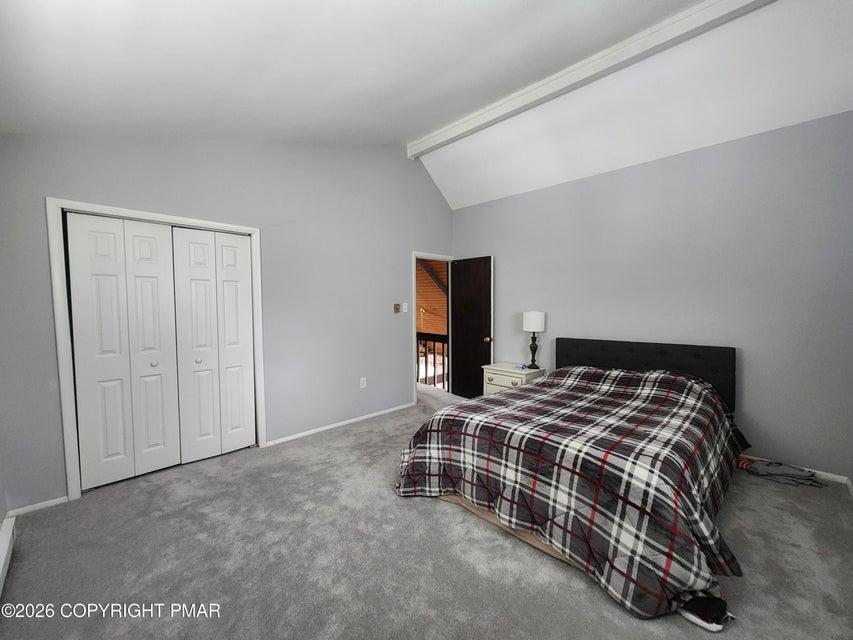 Image 4: This spacious bedroom features a vaulted ceiling a