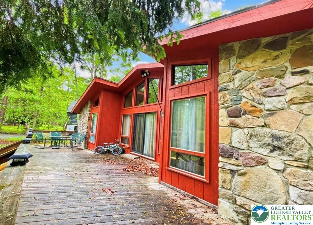 Image 3: Bold red siding and natural stone accents define t