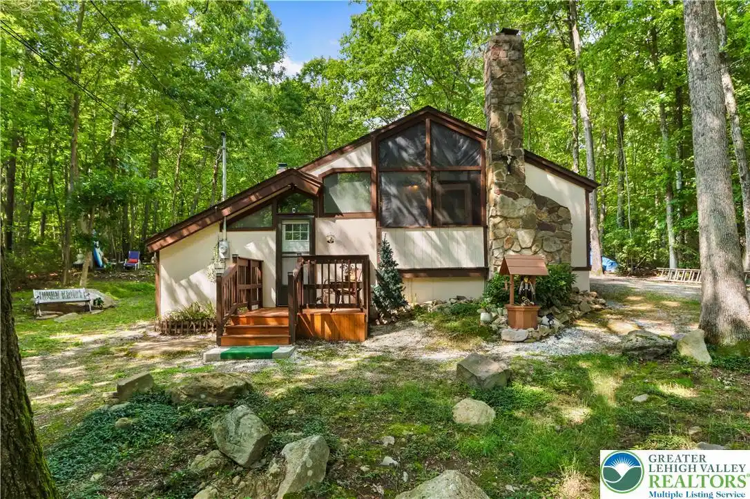 Image 1: A rustic stone chimney accents this wooded retreat