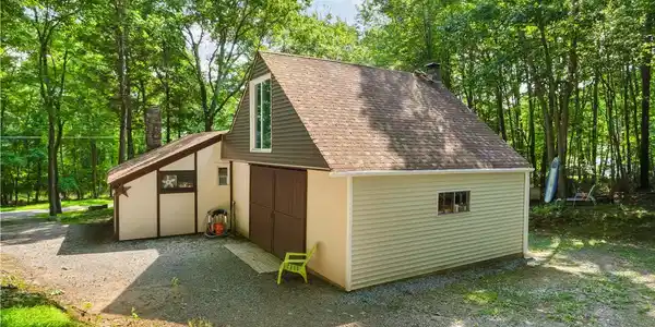 Image 2: Mature trees surround a detached garage with an up