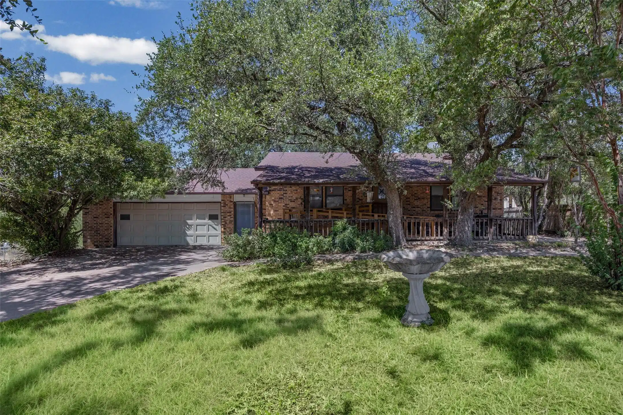 Image 1: Front exterior view framed by grand mature shade t