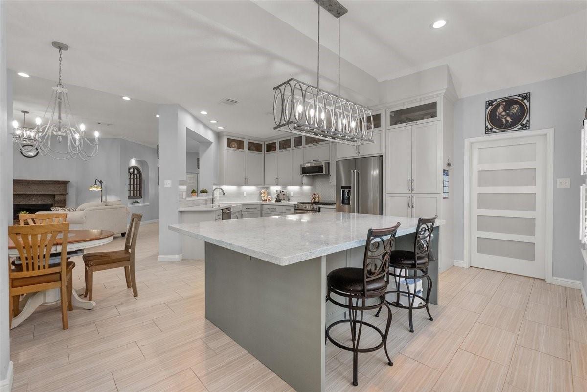 Image 1: This modern kitchen features a large island with b