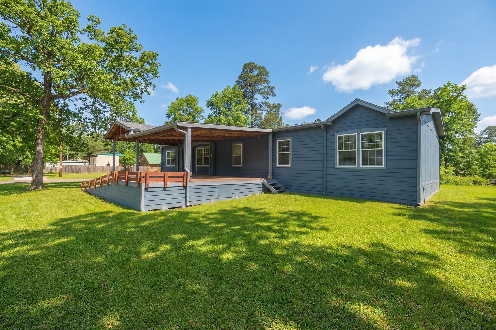 Image 4: Home with a spacious wooden porch, surrounded by m