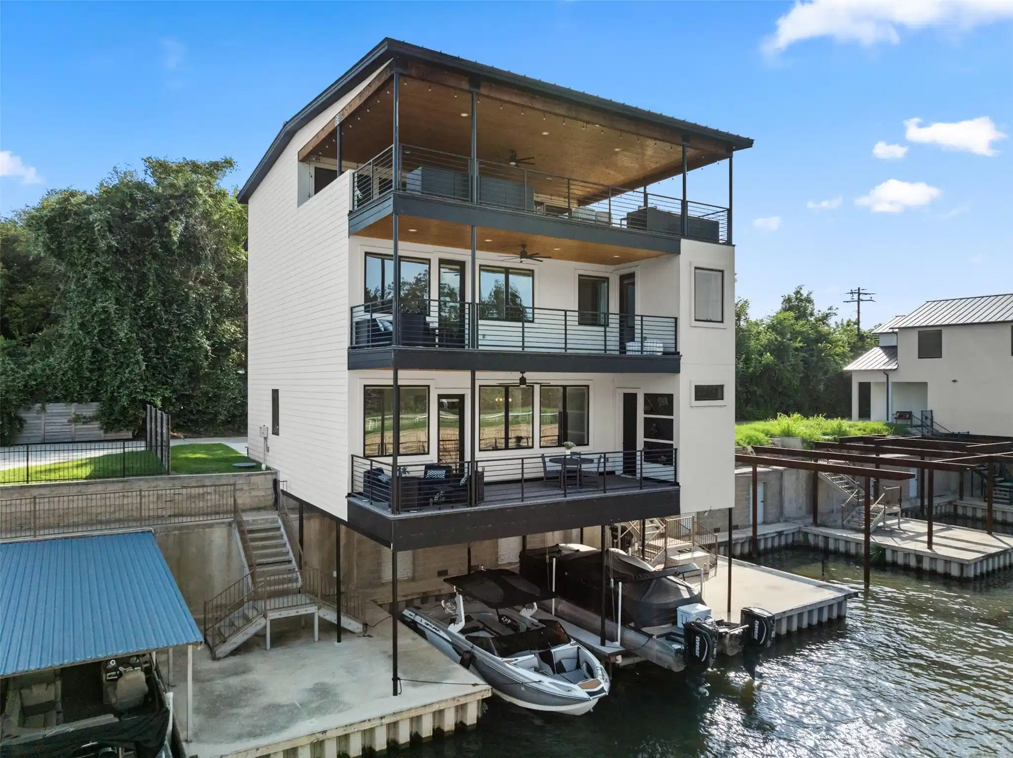 Image 1: This modern, three-story waterfront home features