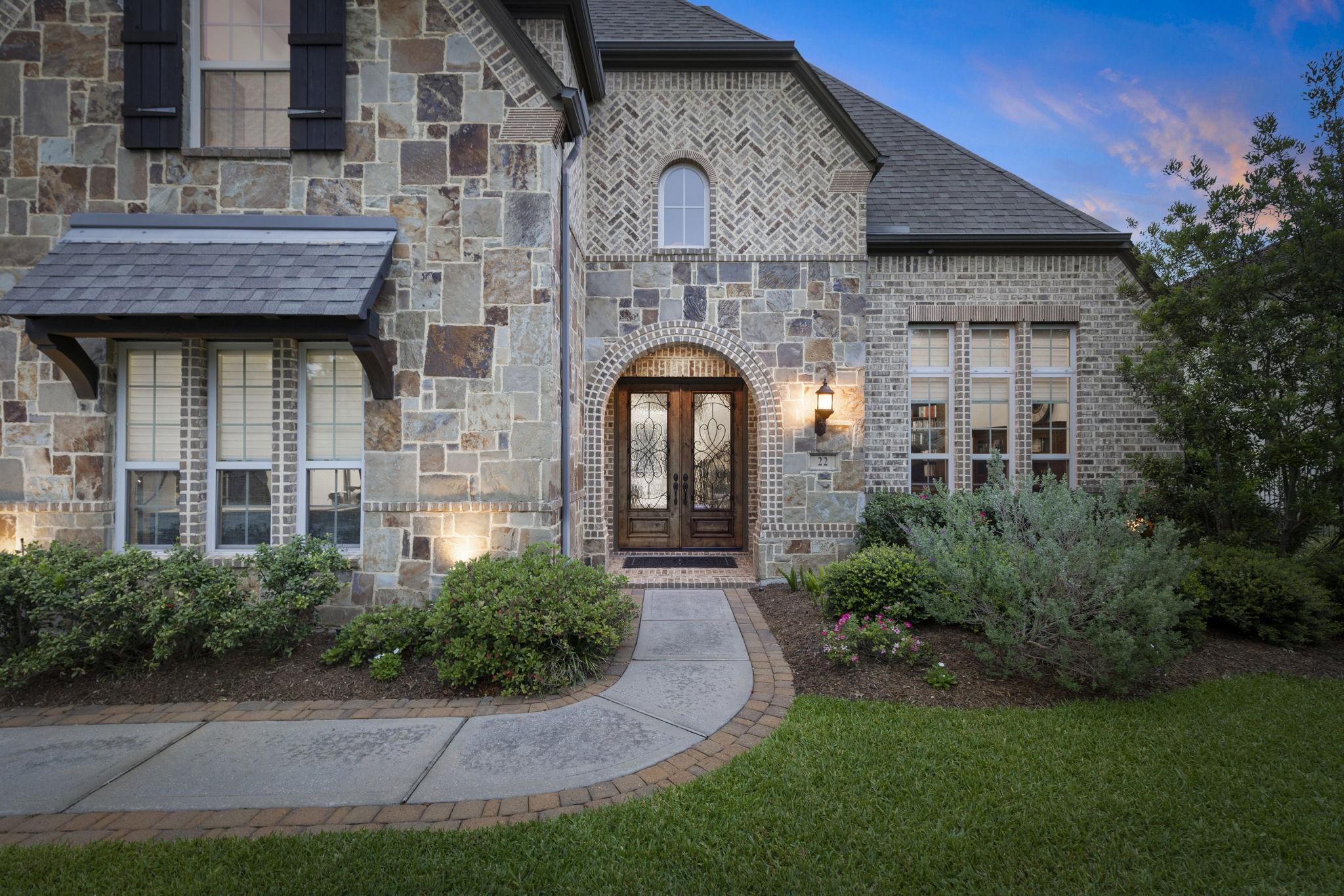 Image 2: Arched entry framed by rich stone and brick masonr