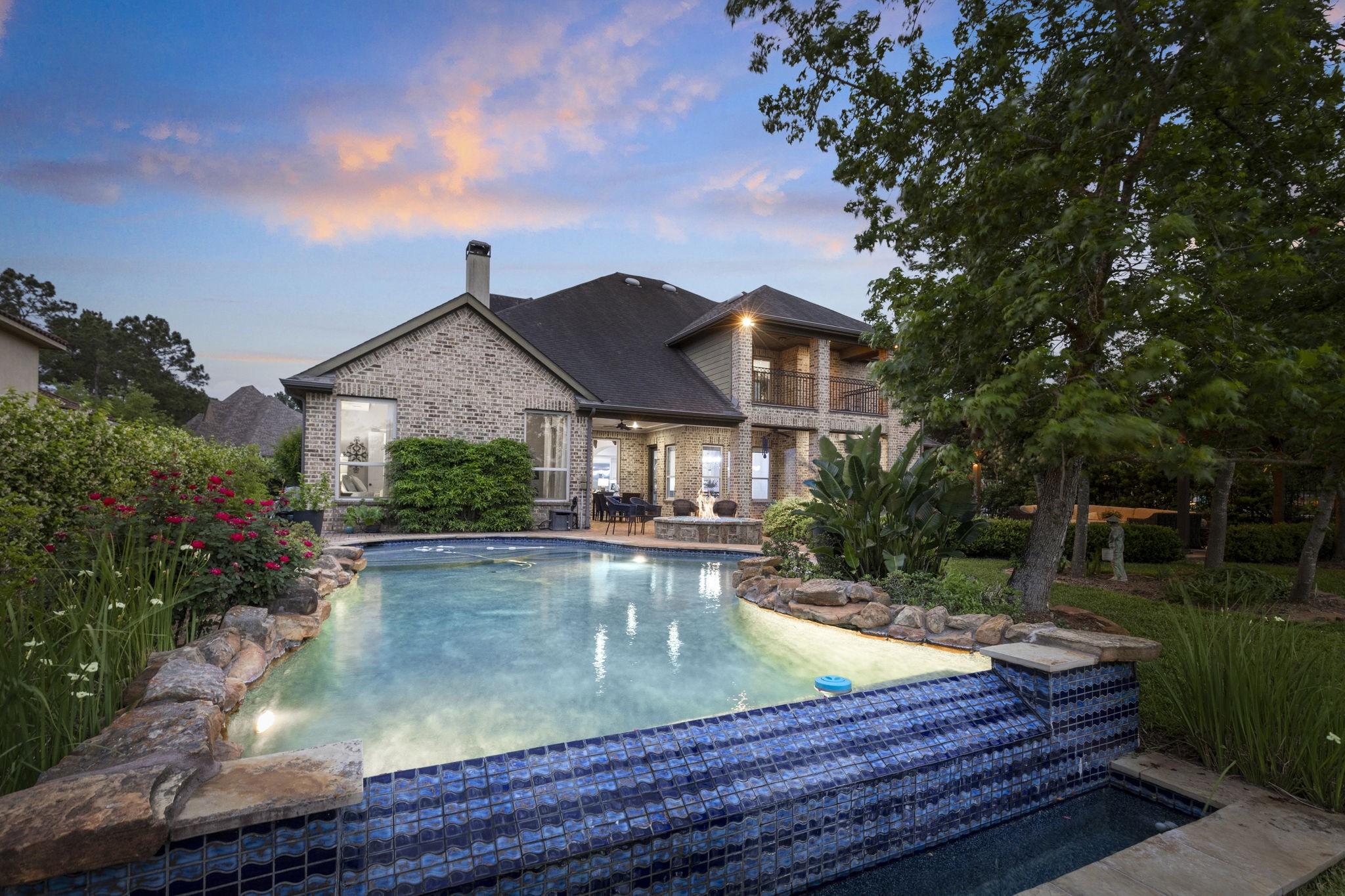 Image 3: Resort-style backyard featuring a freeform pool wi