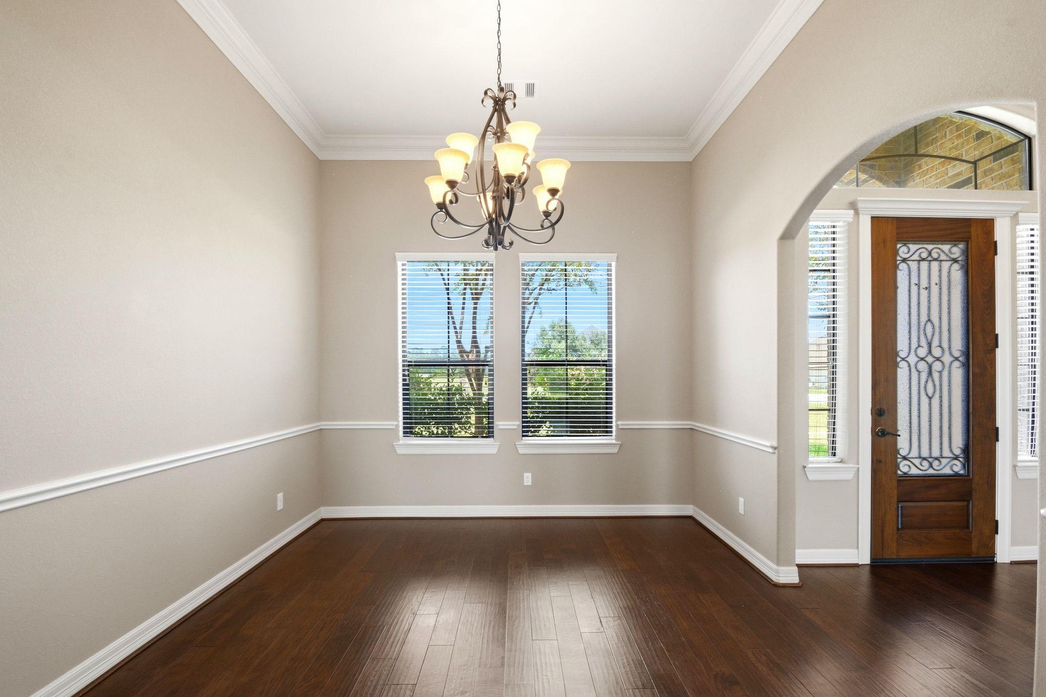 Image 4: Elegant dining area with rich hardwood floors, a c