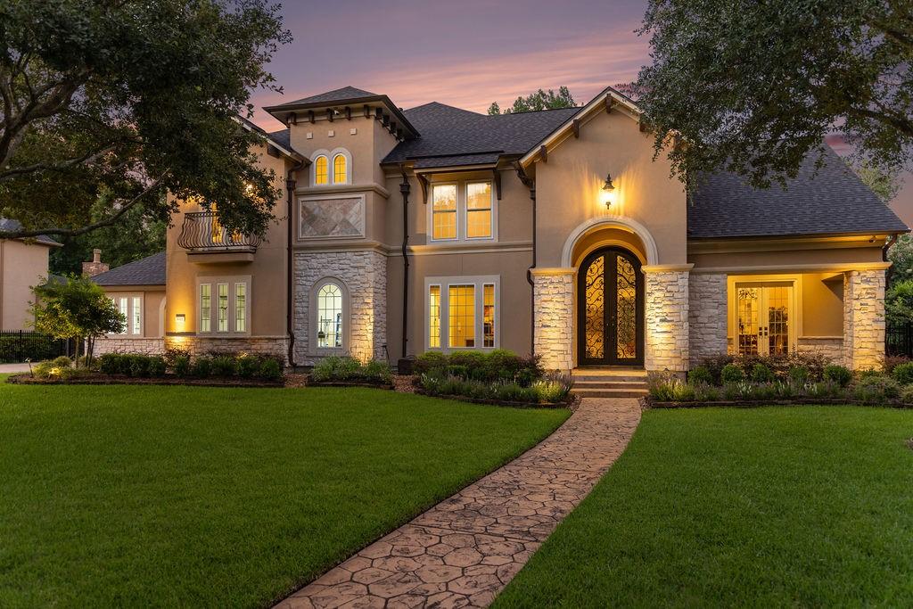 Image 1: This elegant home features a well-lit exterior wit