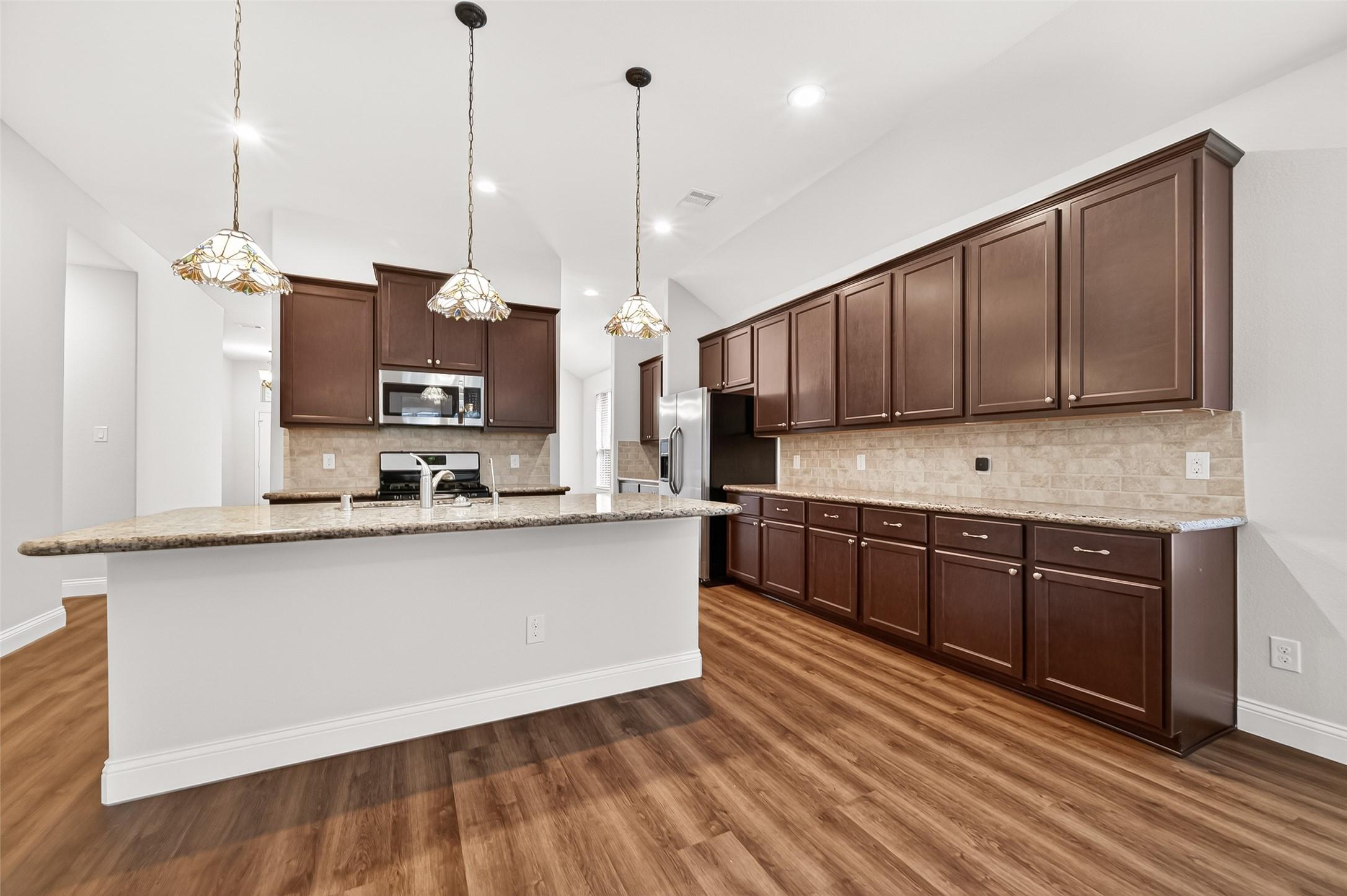Image 4: This spacious kitchen features elegant dark wood c