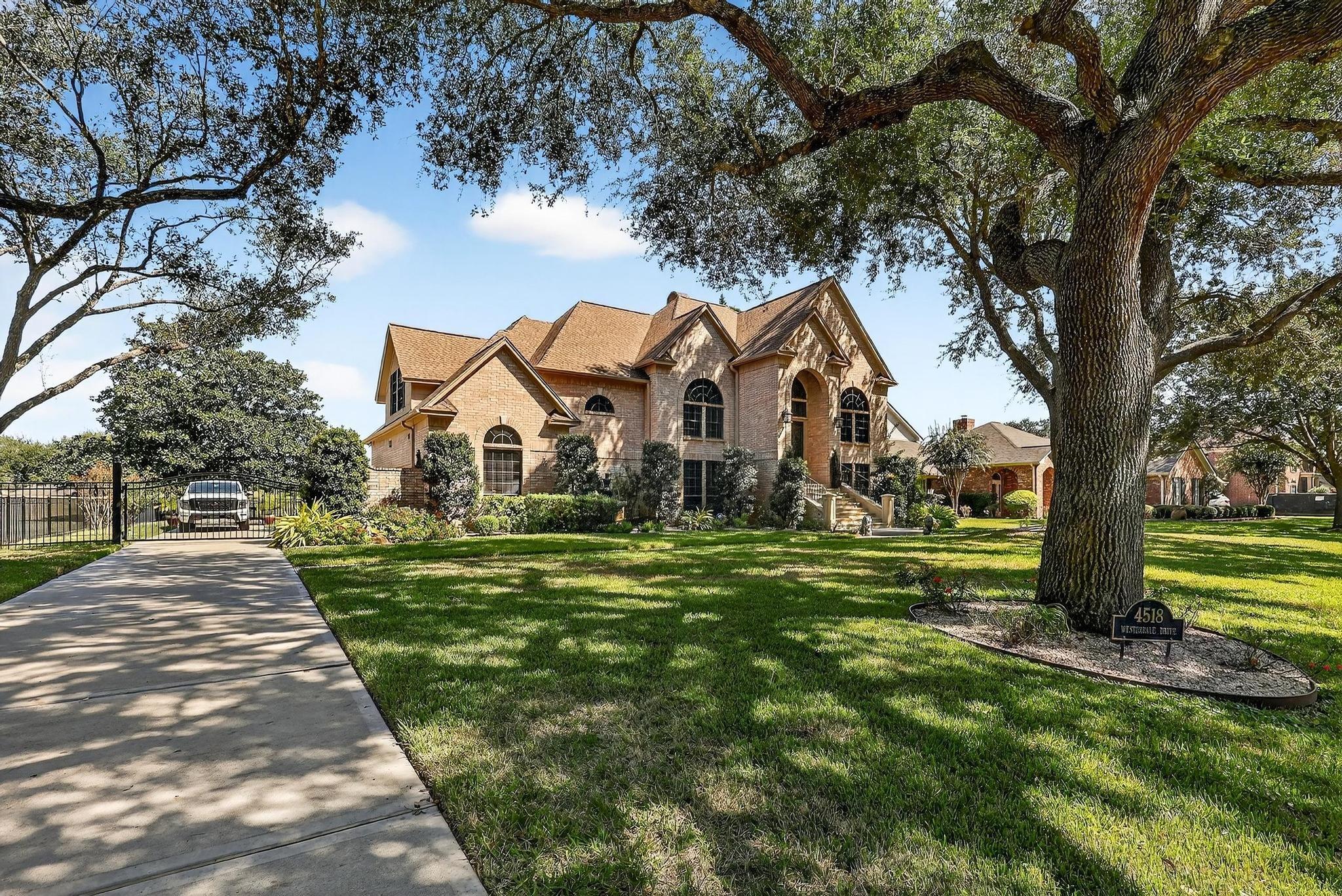 Image 2: Elegant brick residence framed by mature oak trees