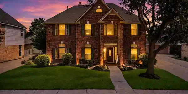 Image 2: Elegant two-story brick home with warm evening lig