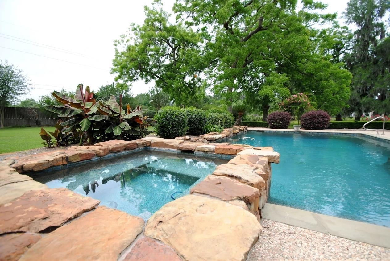 Image 1: This backyard features a stunning pool with a natu