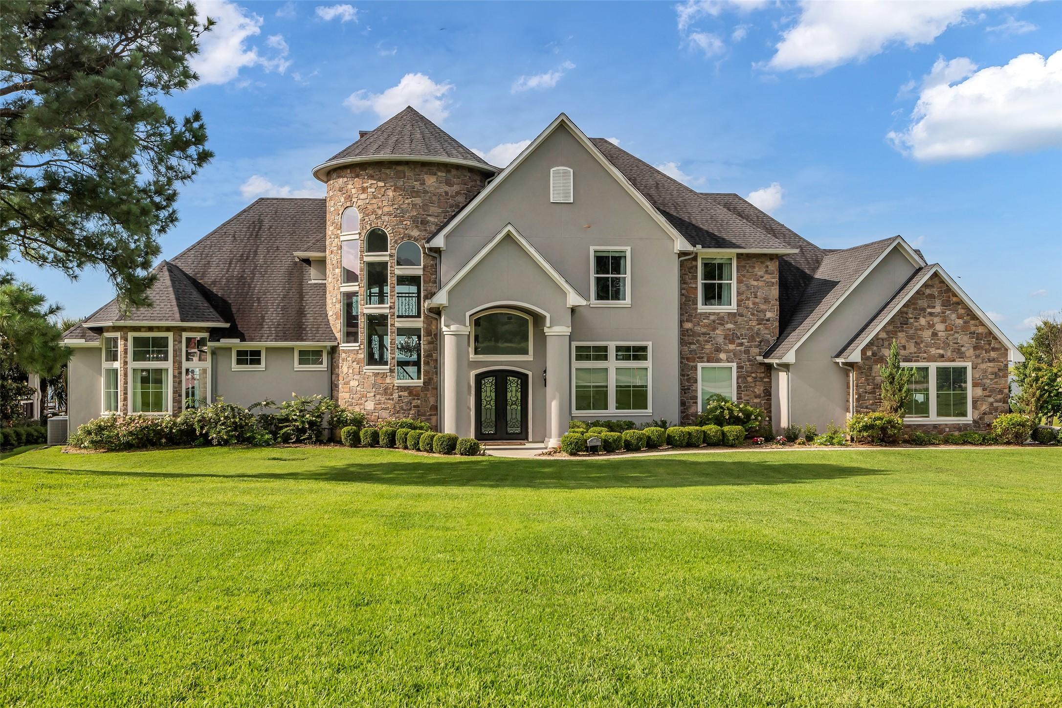 Image 1: This elegant home features a blend of stone and st