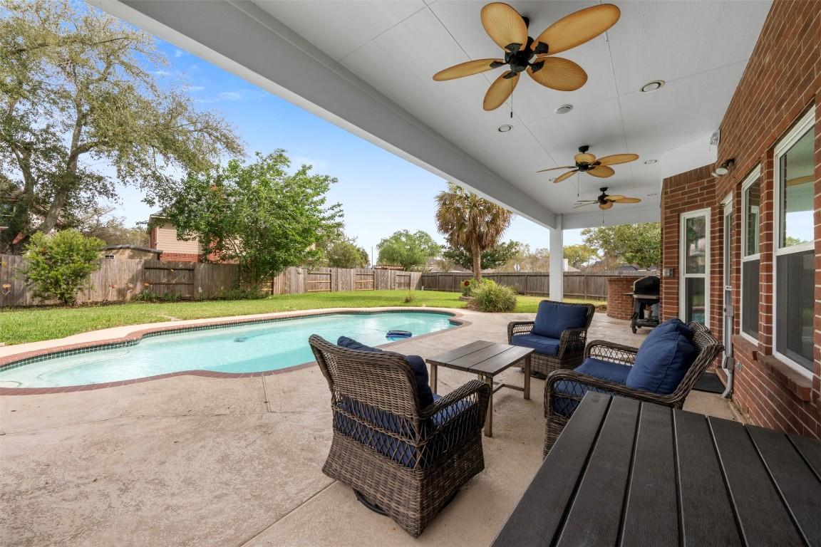 Image 1: Spacious backyard with a covered patio, featuring
