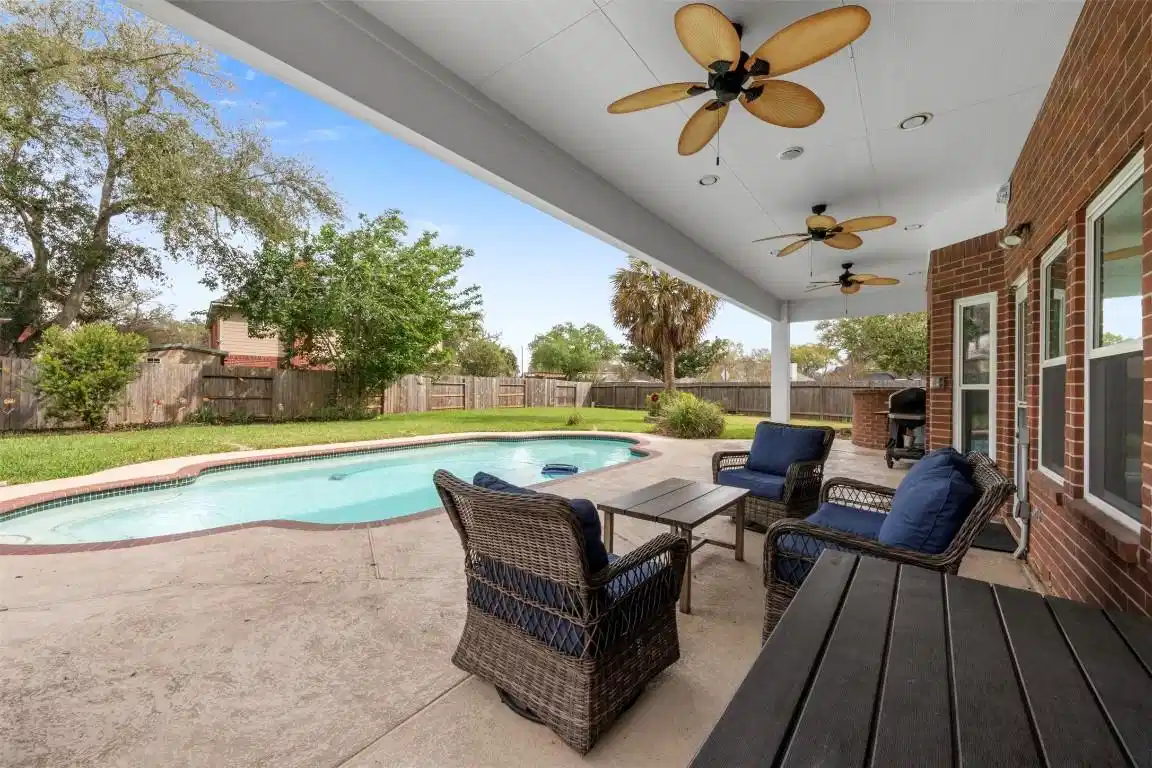 Image 1: Spacious backyard with a covered patio, featuring