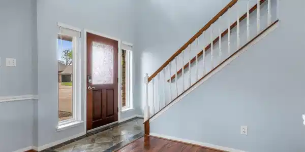 Image 3: Bright entryway with a wooden front door and side