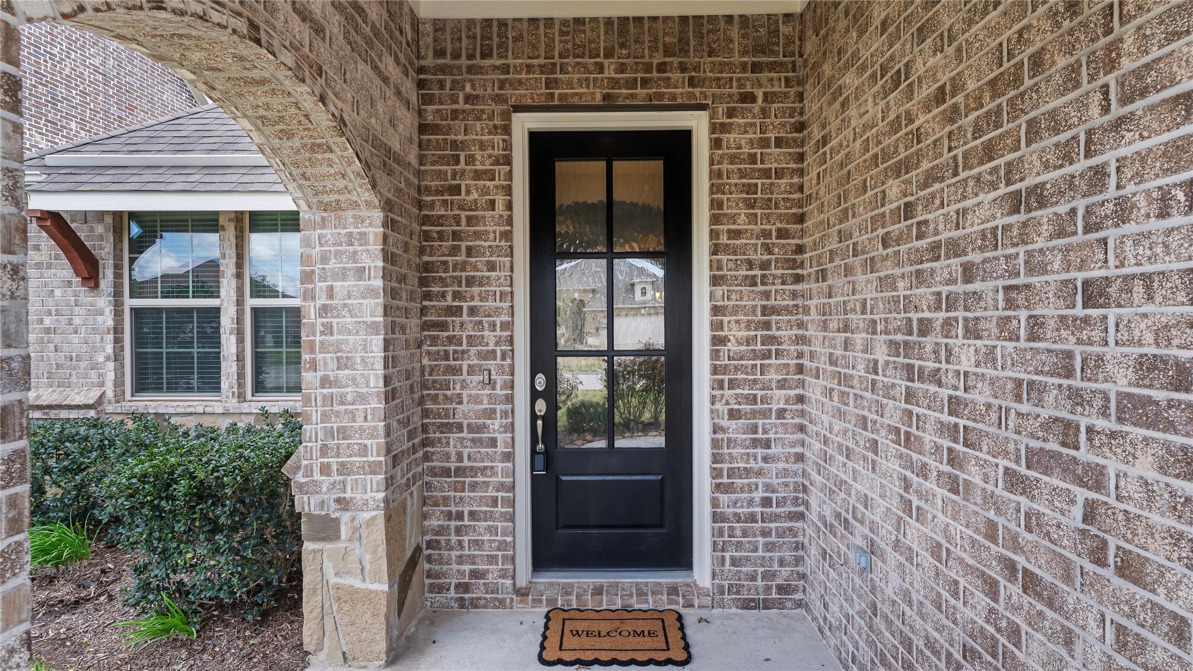 Image 3: Brick entry with wood door and glass panels.