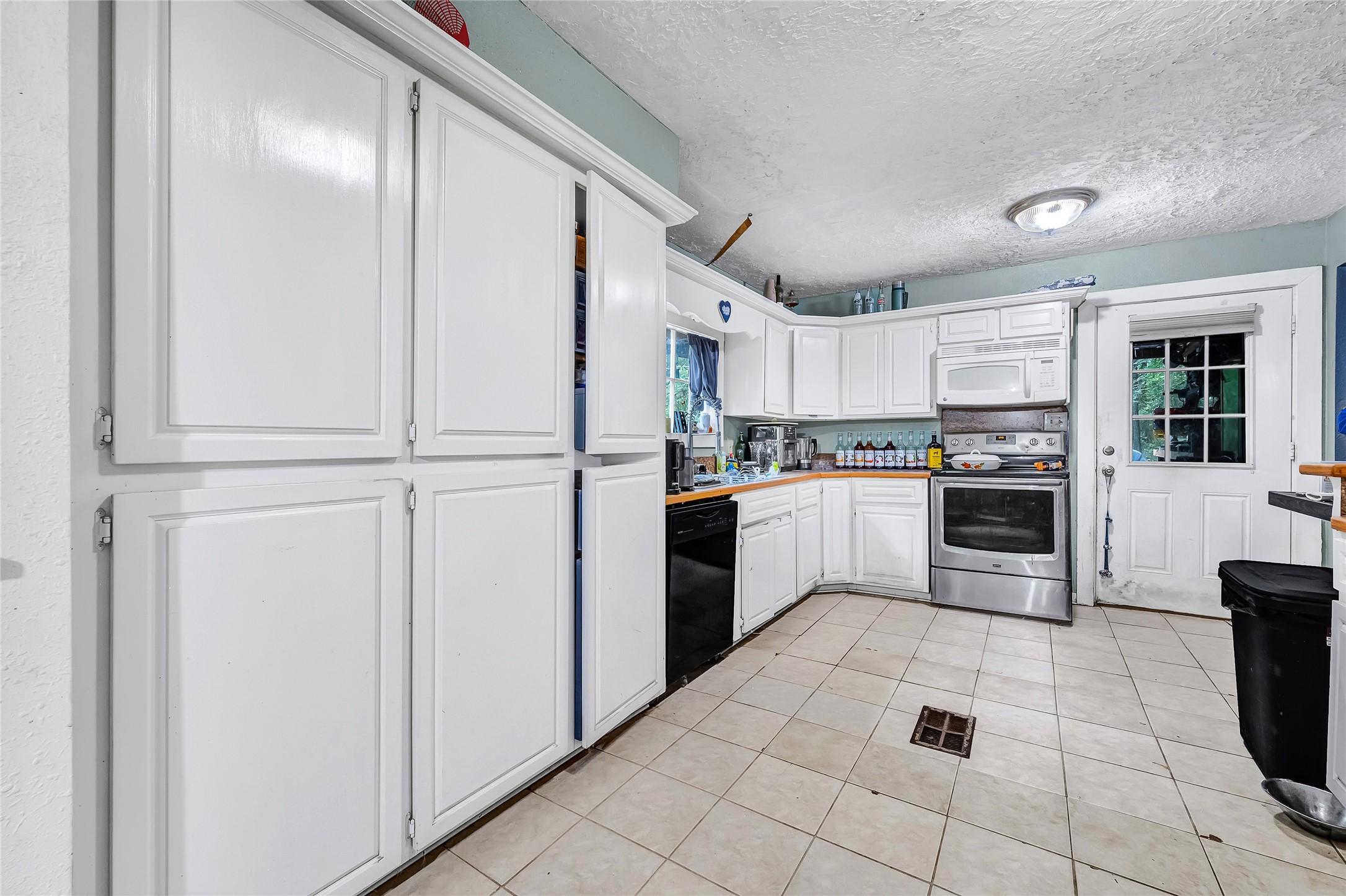 Image 2: Bright kitchen with ample white cabinetry, stainle